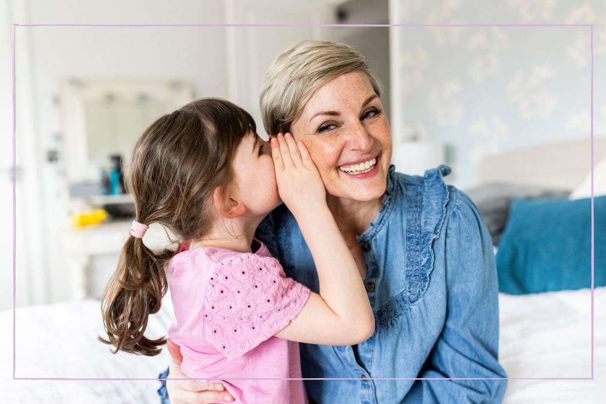  A little girl whispering into her mother's ear. 