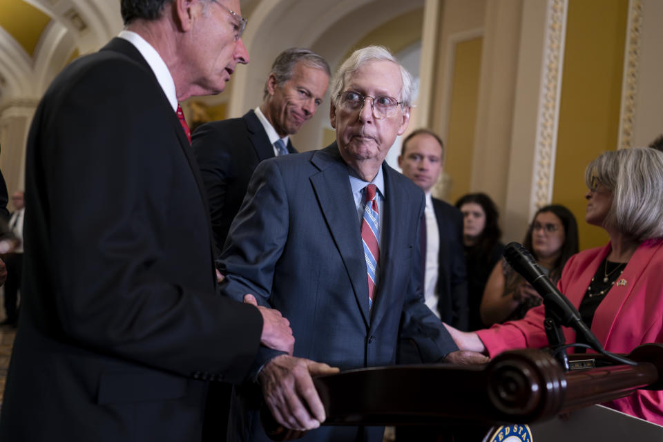 U.S. Senate Minority Leader Mitch McConnell, R-Ky., center, is helped by, from left, Sen. John Barrasso, R-Wyo., Sen. John Thune, R-S.D., and Sen. Joni Ernst, R-Iowa, after the 81-year-old GOP leader froze at the microphones as he arrived for a news conference on July 26, 2023, at the Capitol in Washington. (AP Photo/J. Scott Applewhite)