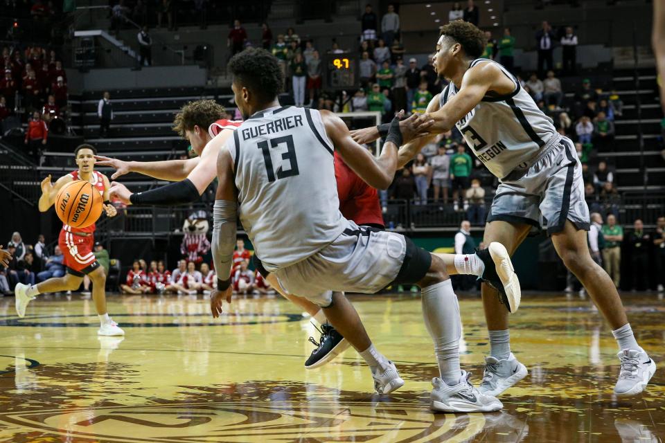 Oregon forward Quincy Guerrier and guard Keeshawn Barthelemy foul Wisconsin guard Max Klesmit in the final minute Tuesday night.