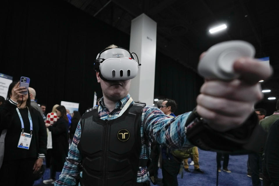 An attendee uses the bHaptics haptic vest during CES Unveiled before the start of the CES tech show Sunday, Jan. 7, 2024, in Las Vegas. The vest is designed to be used in tandem with augmented reality systems to provide haptic feedback in video games. (AP Photo/Ryan Sun)