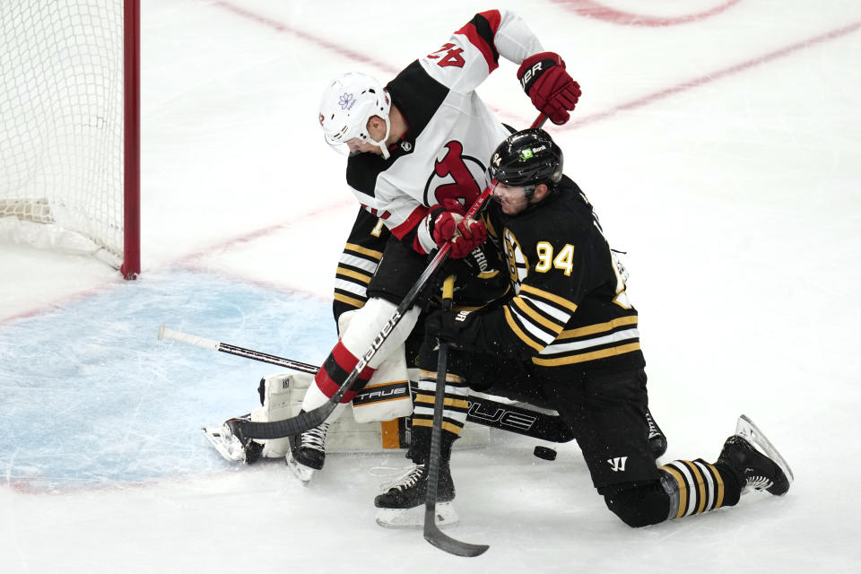 Boston Bruins center Jakub Lauko (94) tries to clear New Jersey Devils center Curtis Lazar (42) away from the goal during the first period of an NHL hockey game, Monday, Jan. 15, 2024, in Boston. (AP Photo/Charles Krupa)