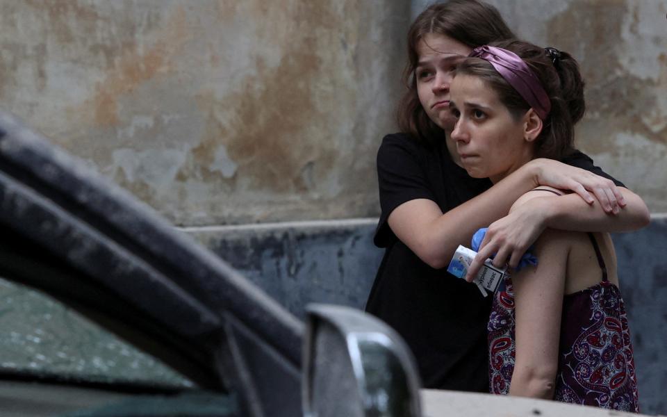 Residents react at a site of a residential building hit by a Russian missile strike