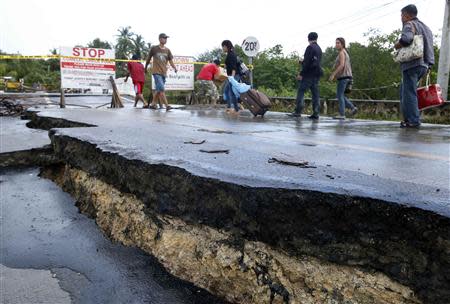 Commuters walk near the damaged portion of a highway in Loay, Bohol, after an earthquake struck central Philippines October 17, 2013. REUTERS/Erik De Castro