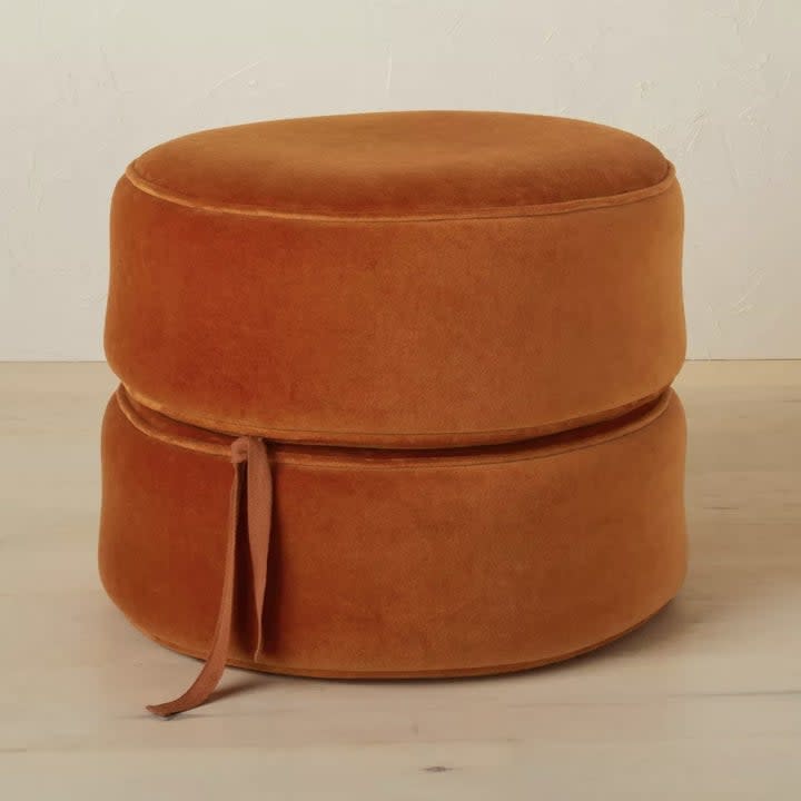 the round rust colored pouf with cushions stacked together