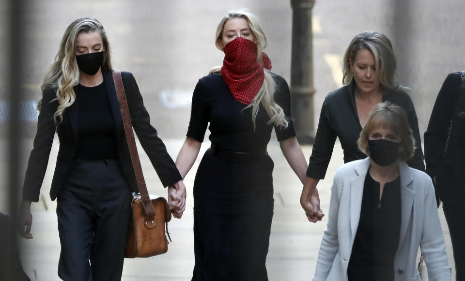 Actress Amber Heard, center, arrives at the High Court in London, Tuesday, July 7, 2020. Johnny Depp has a starring role in a real-life courtroom drama in London, where he is suing a tabloid newspaper for libel over an article that branded him a "wife beater." On Tuesday, a judge at the High Court is due to begin hearing Depp's claim against The Sun's publisher, News Group Newspapers, and its executive editor, Dan Wootton, over the 2018 story alleging he was violent and abusive to then-wife Amber Heard. Depp strongly denies the claim. (AP Photo/Alastair Grant)