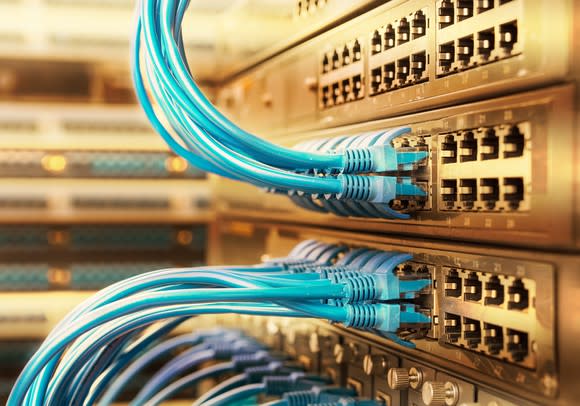 Networking switches in a rack with neatly organized blue networking cable plugged in