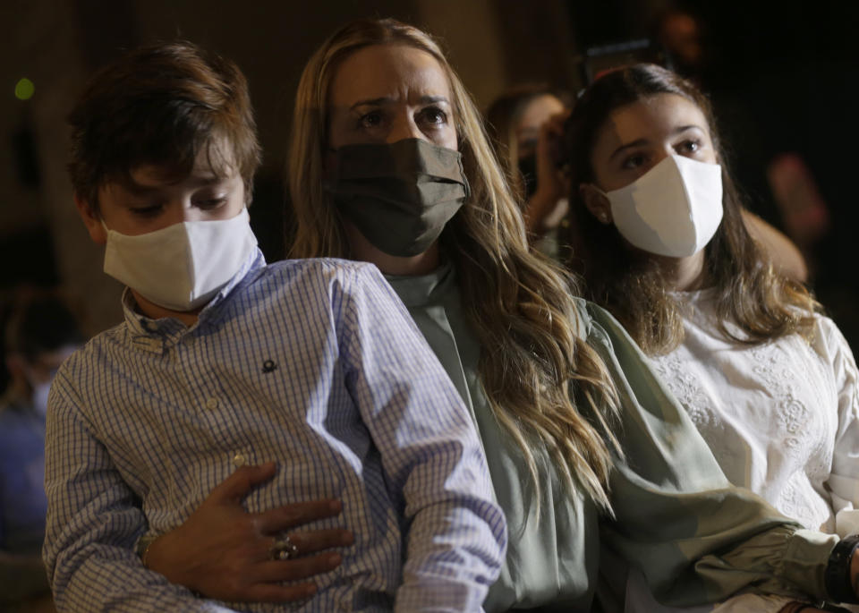 Lilian Tintori sits with her son and daughter, as she listens to her husband Leopoldo Lopez during a news conference in Madrid on Tuesday, Oct. 27, 2020. Prominent opposition activist Leopoldo López who has abandoned the Spanish ambassador's residence in Caracas and left Venezuela after years of frustrated efforts to oust the nation's socialist president is holding a news conference in Madrid. (AP Photo/Andrea Comas)