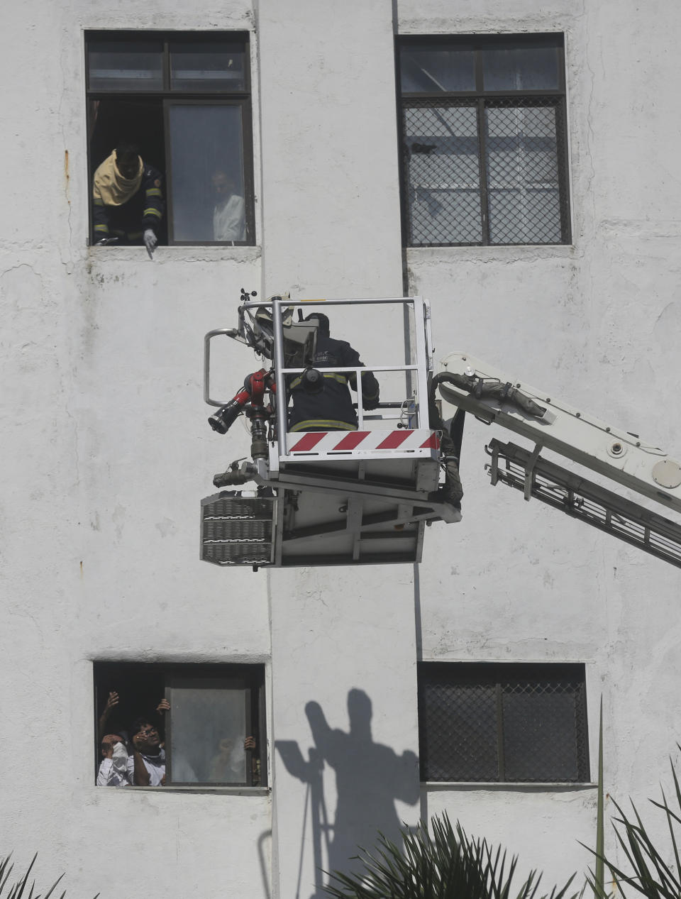 People awaiting rescue stand near the windows of a nine-story building with offices of a state-run telephone company during a fire in Mumbai, India, Monday, July 22, 2019. (AP Photo/Rafiq Maqbool)