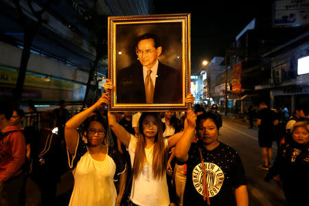 Women pose with a portrait of Thailand's King Bhumibol Adulyadej, as others line up to hold the portrait, after the announcement of the king's death, outside Siriraj hospital in Bangkok,, Thailand October 13, 2016. REUTERS/Jorge Silva