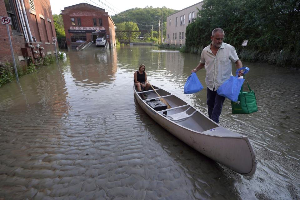 FILE - Jodi Kelly, seated center, practice manager at Stonecliff Veterinary Surgical Center, behind, and her husband Veterinarian Dan Kelly, right, use a canoe to remove surgical supplies from the flood damaged center, July 11, 2023, in Montpelier, Vt. The supplies included orthopedic implants for an upcoming surgery on a dog. (AP Photo/Steven Senne, File)