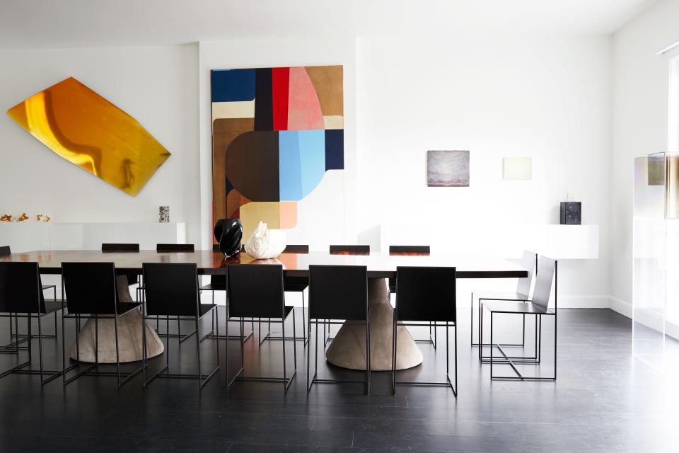 The gallery-like dining room features a series of striking contemporary artworks, including an untitled multicolored oil on canvas by Svenja Deininger and a golden wall sculpture by Nicola Martini (made of wax and bithumen on plexiglas). A table from the 1960s, designed by Jorge Zalszupin with a jacarandá top and sturdy concrete bases covered in suede, quietly anchors the space. The minimalist metal chairs, called Slim Sissi, were designed by Maurizio Peregalli for Zeus Noto.