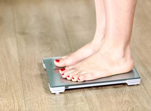 Top view of feet on weighing scale. Women weigh on a weight balance scale  after diet control. Healthy body weight. Weight and fat loss concept. Weight  measure machine. Body Mass Index or