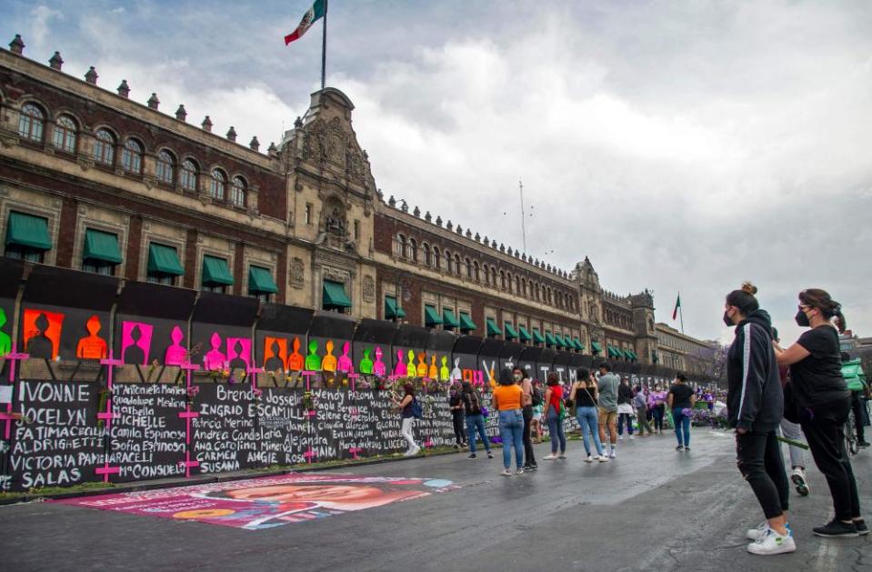 Women look at the barriers covered with the names of femicide victims surrounding the national palace.