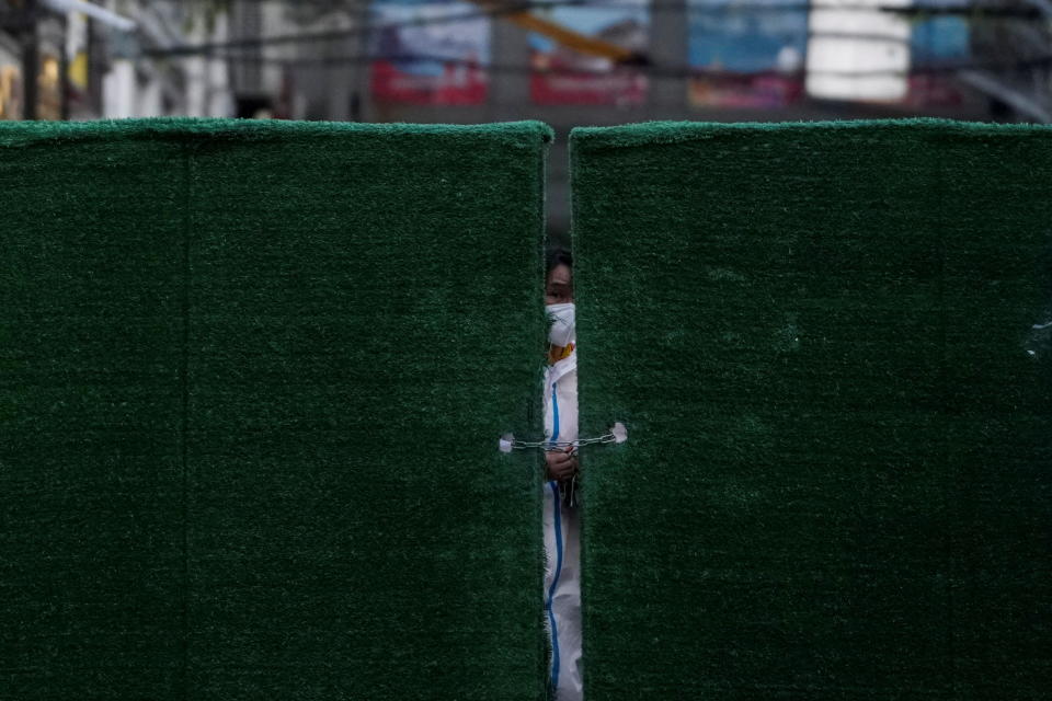 A worker in a protective suit locks a barrier of a residential area in Shanghai on May 4. Source: Reuters