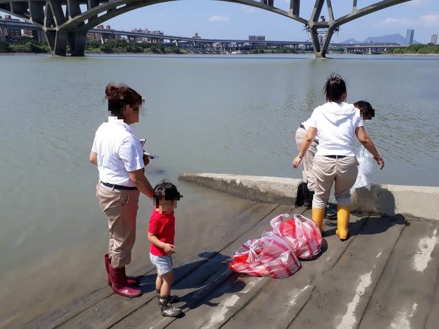 放生者一家以塑膠袋盛裝動物，準備於河濱公園放生。（台北市動保處提供）