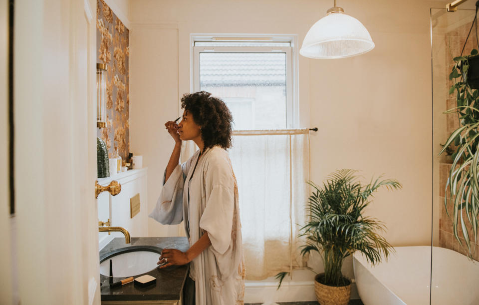 a woman doing her makeup in the bathroom