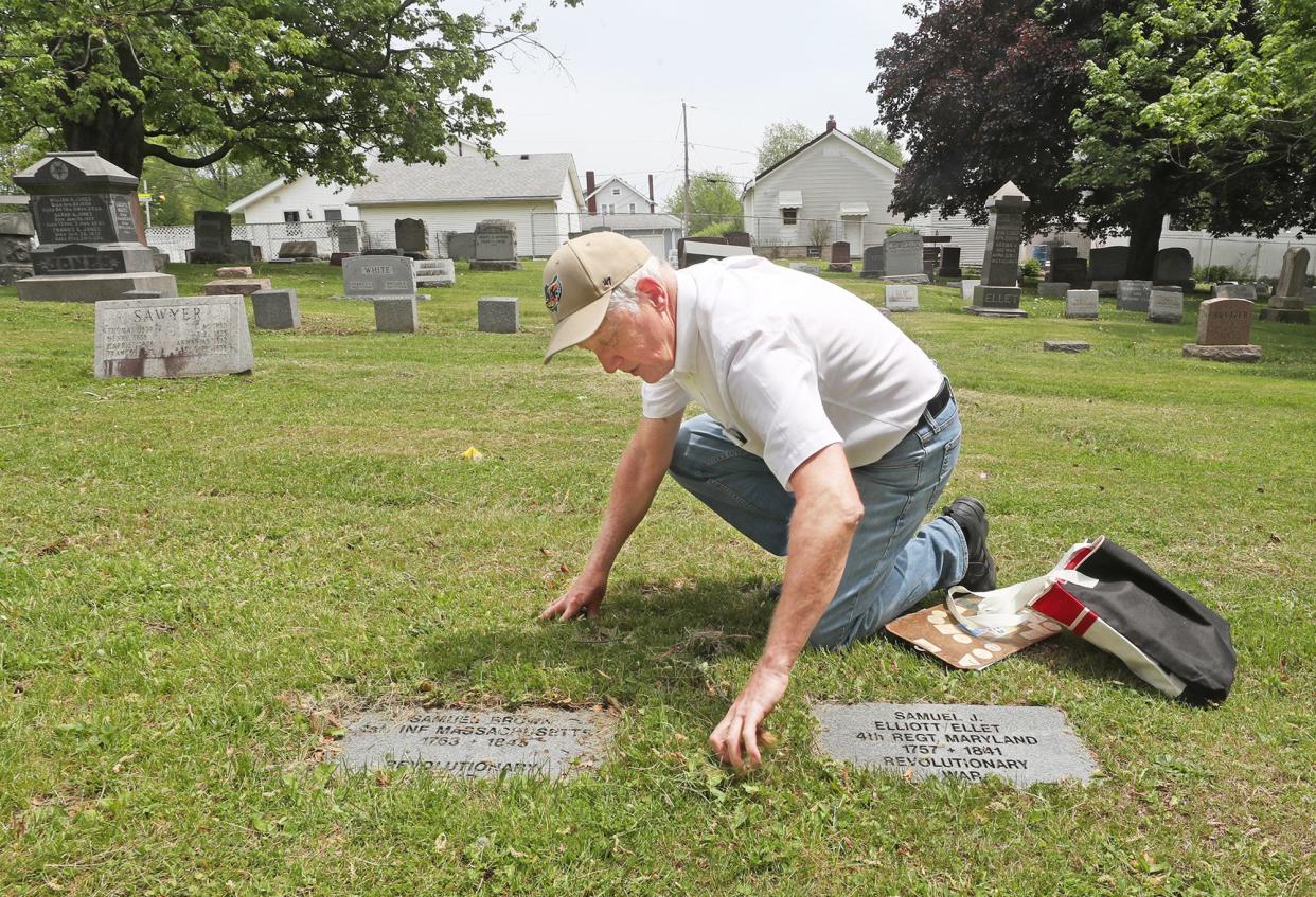 Jim Weyrick cleans off the headstones of Revolutionary War veterans Samuel Brown and Samuel J. Elliott/Ellet at 200-year-old Ellet Cemetery in Akron.