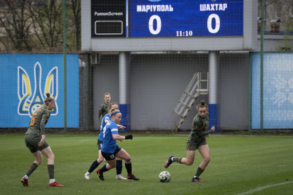 Players of a women's football team from Mariupol and Shakhtar challenge for the ball during Ukrainian championship match in Kyiv, Ukraine, Tuesday, April 18, 2023. After their city was devastated and captured by Russian forces, the team from Mariupol rose from the ashes when they gathered a new team in Kyiv. They continue to play to remind everyone that despite the occupation that will soon hit one year, Mariupol remains a Ukrainian city. (AP Photo/Efrem Lukatsky)