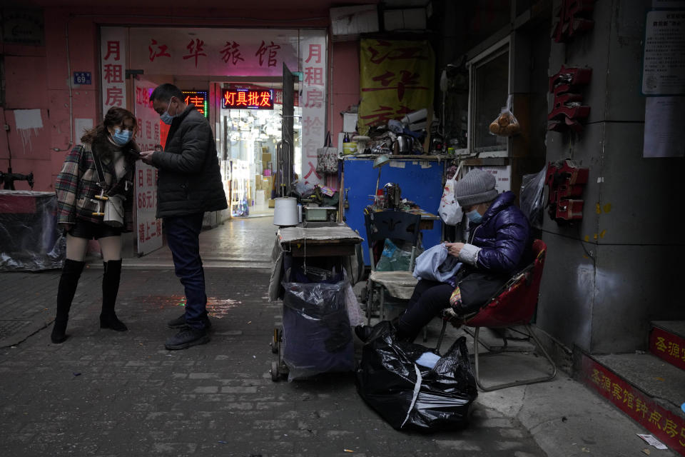 Residents wear masks as they past by a seamstress along an alleyway in Wuhan in central China's Hubei province on Friday, Jan. 22, 2021. Life appears to be back to normal on the eve of the anniversary of the 76-day lockdown in the central Chinese city where the coronavirus was first detected. (AP Photo/Ng Han Guan)