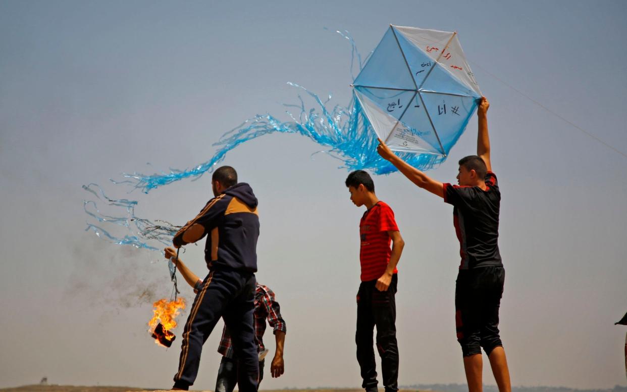 Palestinian protestors prepare to fly a kite loaded with an incendiary during a demonstration along the border with Israel east of Jabalia in the central Gaza Strip - AFP