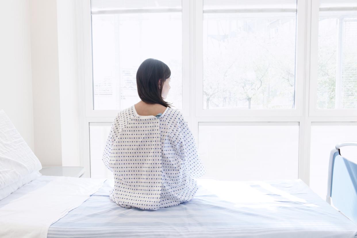 Patient sitting on hospital bed, rear view.