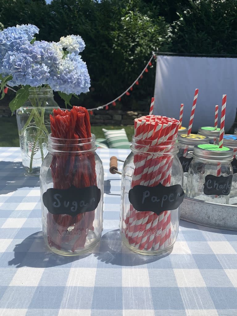 diy backyard movie night ideas two mason jars of sugar licorice straws and paper straws on a picnic table