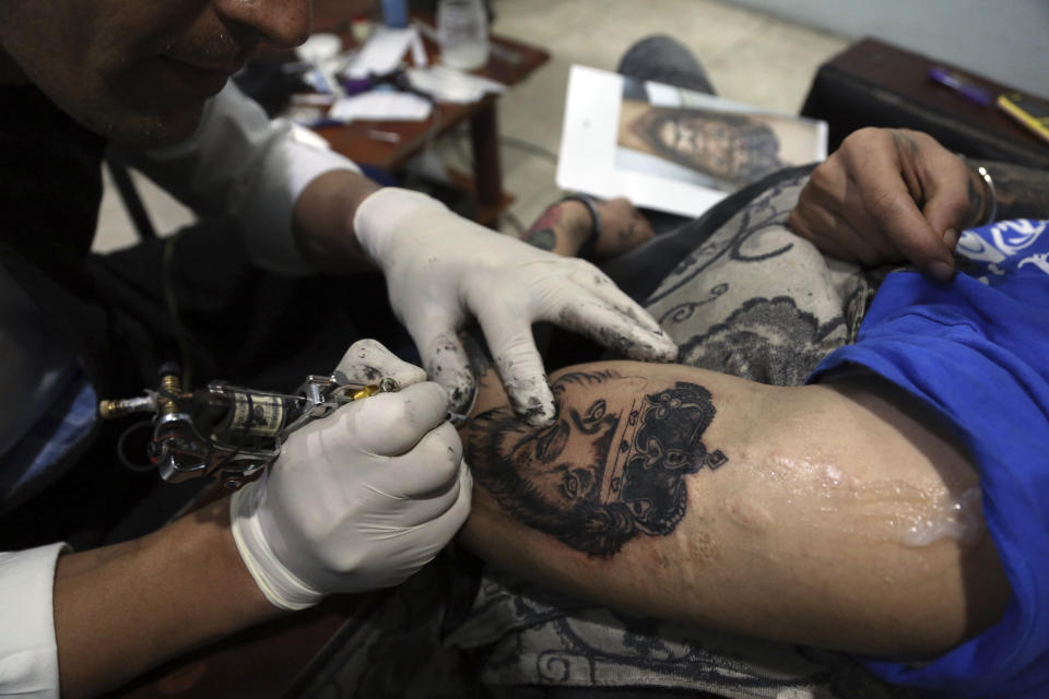 In this Wednesday, Nov. 20, 2019, photo, Omid Noori, 23, right, gets a lion tattoo on his left arm by Nazeer Mosawi, a tattoo artist in Kabul, Afghanistan. Mosawi, 42, fought for seven years in Afghanistan’s civil war with the Islamic insurgents. He says he is still fighting the war, but this time his battle is against society’s conservatism, with his tattoo machine as his weapon.(AP Photo/Rahmat Gul)