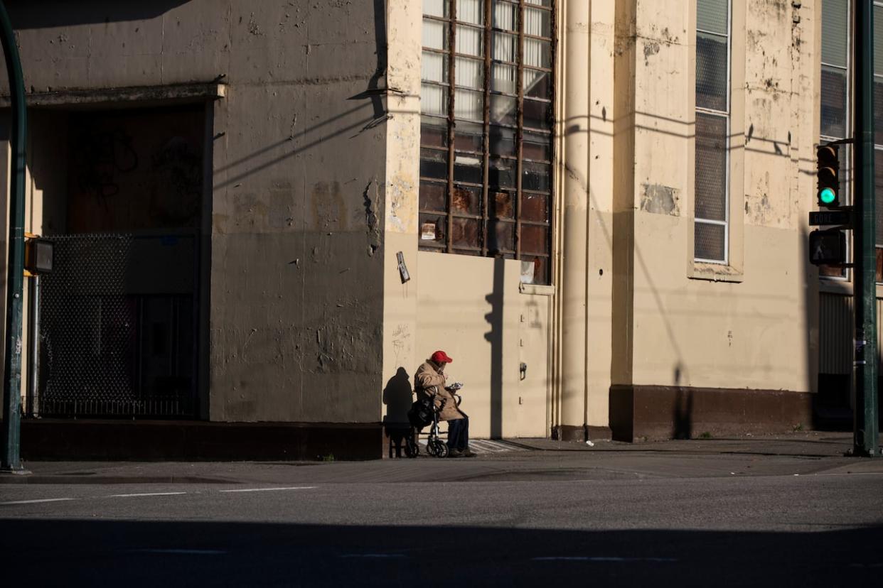 An elderly man sits on a street corner in Vancouver in December 2020. A recent Statistics Canada study found disabled people are overrepresented among recent evictees. (Ben Nelms/CBC - image credit)