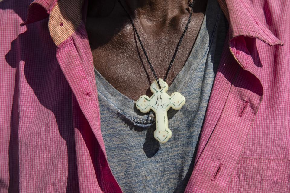 A Tigray refugee who fled the conflict in the Ethiopia's Tigray with a Cross around his neck arrives on the banks of the Tekeze River on the Sudan-Ethiopia border, in Hamdayet, eastern Sudan, Tuesday, Dec. 1, 2020. (AP Photo/Nariman El-Mofty)