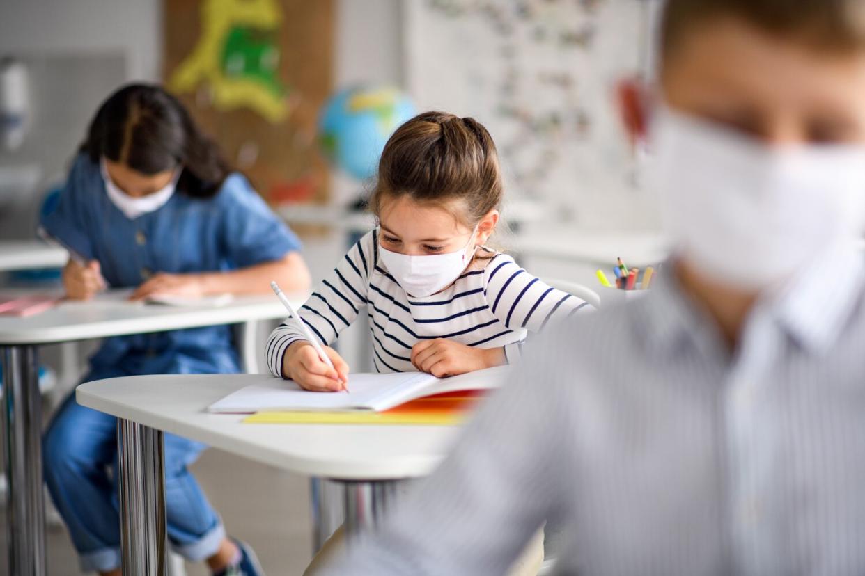 Small children with face mask back at school after covid-19