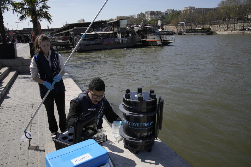 Senior technician Omar Bach-Rais testes water samples from the River Seine for analysis as Aurelie Lemaire, a microbiology research intern looks on, in Paris, Wednesday, April 5, 2023. A costly and complex clean-up is resuscitating the River Seine just in time for it to play a starring role in the 2024 Paris Olympics. The city and its region are rushing to make the Seine's murky waters swimmable, so it can genuinely live up to its billing as the world’s most romantic river. (AP Photo/Christophe Ena)