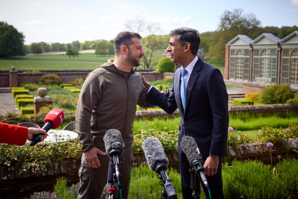 Ukrainian President Volodymyr Zelensky and British Prime Minister Rishi Sunak speak to each other in a garden.