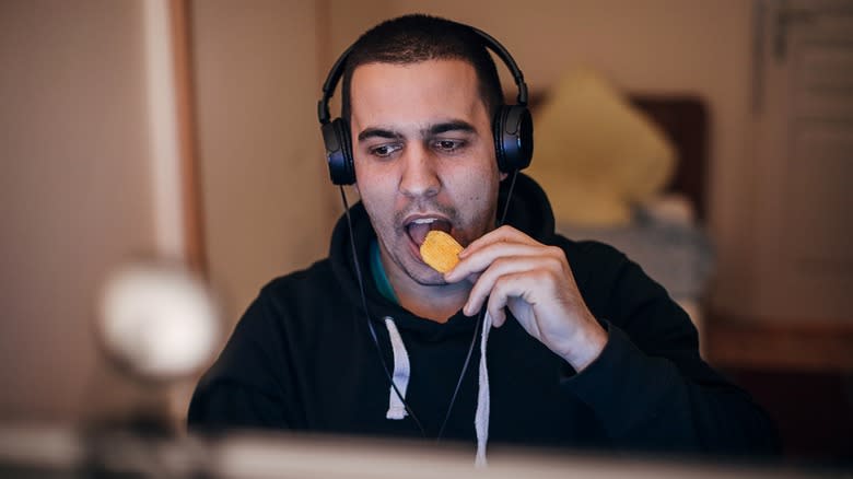 Man wearing headphones eating chips