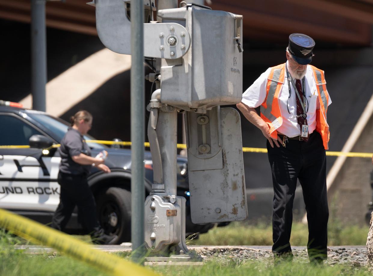 An Amtrak worker stands at the scene of a fatal wreck where a train hit an SUV at McNeil Road at Interstate 35 in Round Rock on Wednesday.