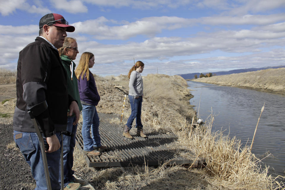 FILE - In this March 2, 2020, file photo, farmer Ben DuVal with his wife, Erika, and their daughters, Hannah, third from left, and Helena, fourth from left, stand near a canal for collecting run-off water near their property in Tulelake, Calif. Federal officials announced Wednesday that farmers who rely on a massive irrigation project spanning the Oregon-California border will get 8% of the deliveries they need amid a severe drought. (AP Photo/Gillian Flaccus, File)