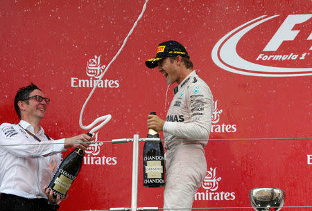 Formula One - Japanese Grand Prix - Suzuka Circuit, Japan- 9/10/16. Mercedes' drivers Nico Rosberg of Germany and a team member splash champagne to celebrate wining during an awarding ceremony at the race. REUTERS/Toru Hanai