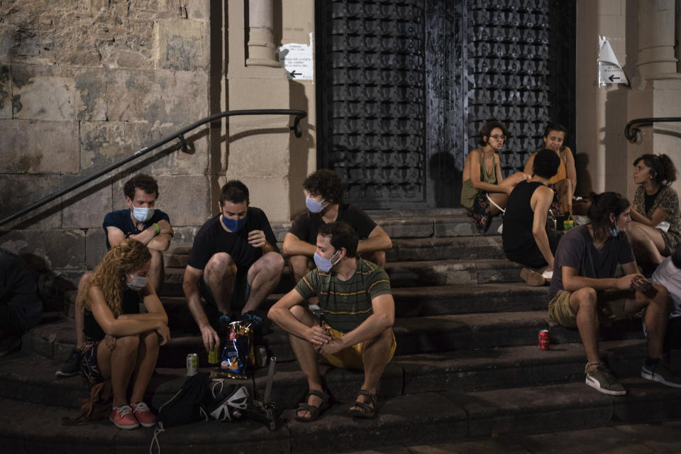 People gather at a public square at night in Gracia neighborhood, Barcelona, Spain, Friday, July 24, 2020. Health authorities in the northeastern region of Catalonia have ordered nightclubs to be fully closed and bars and restaurant in Barcelona to shut down by midnight in an effort to stem the spread of the new coronavirus. (AP Photo/Felipe Dana)