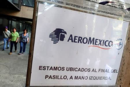 People walk past a sign with the logo of Aeromexico at their office in Caracas, Venezuela June 23, 2016. REUTERS/Carlos Garcia Rawlins - RTX2HVHW