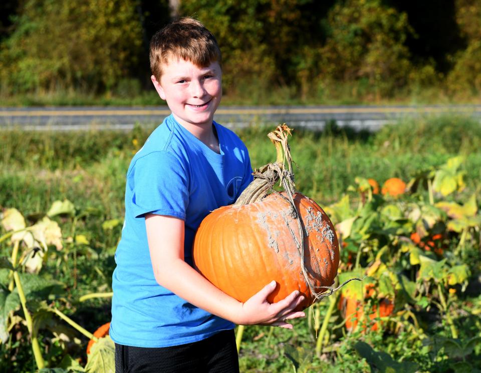 Seidon Shaffer holds the pumpkin he picked at Adkins Farm Market Monday, Oct. 2, 2023, in Salisbury, Maryland.
