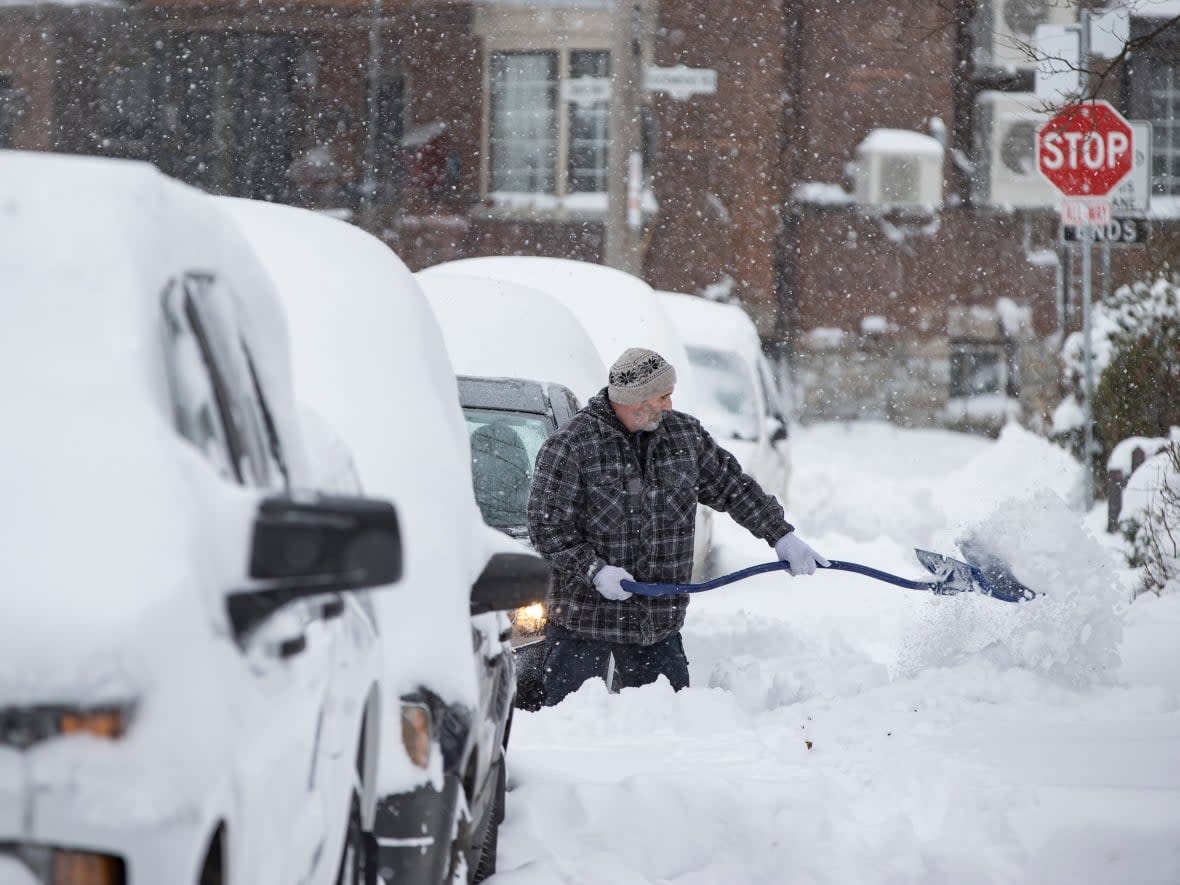 A man digs out a car in Toronto's Beach neighbourhood after a significant dump of snow on Jan. 17, 2022. (Evan Mitsui/CBC - image credit)