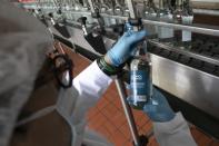 A worker inspects a bottle of antiseptic alcohol at the Santa Teresa rum factory in La Victoria, Aragua state, Venezuela, Wednesday, April 1, 2020. Venezuela's premier rum distillery and one of Venezuela's few private businesses says that most of its production will be for antiseptic alcohol, in an effort to help contain the spread of the new coronavirus. (AP Photo/Ariana Cubillos)