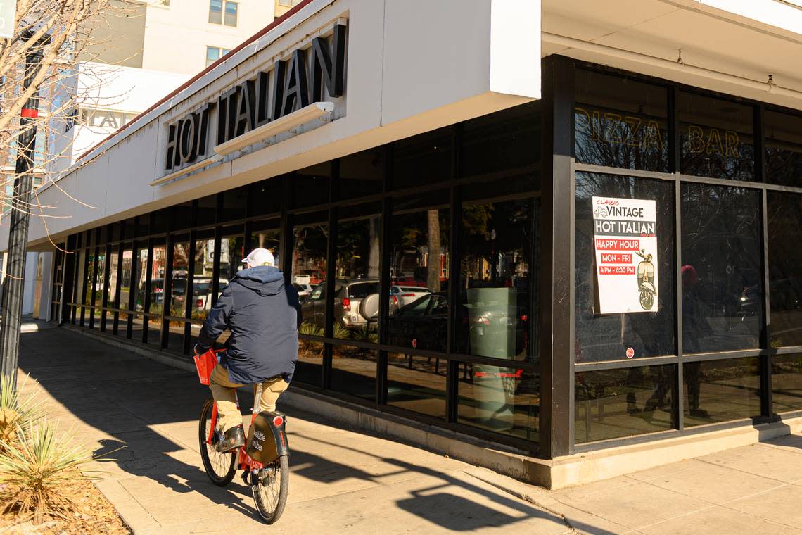 A man rides by Hot Italian in downtown Sacramento in 2019, as patrons inside enjoy a last meal before the restaurant closes its doors permanently. Jason Pierce/jpierce@sacbee.com