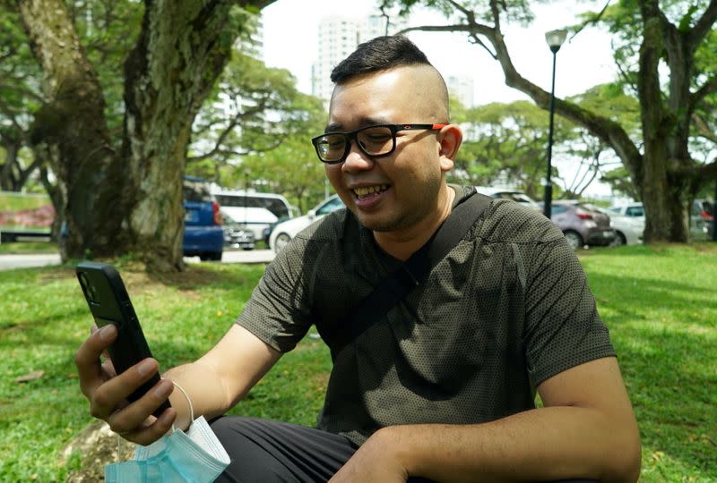 Singaporean Mohammad Faris Abdullah, 37, uses his smartphone at a parking lot where he once lived in his car for about six months, in Singapore