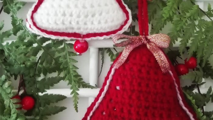 one crocheted christmas bell ornament in red, one crocheted christmas bell ornament in white