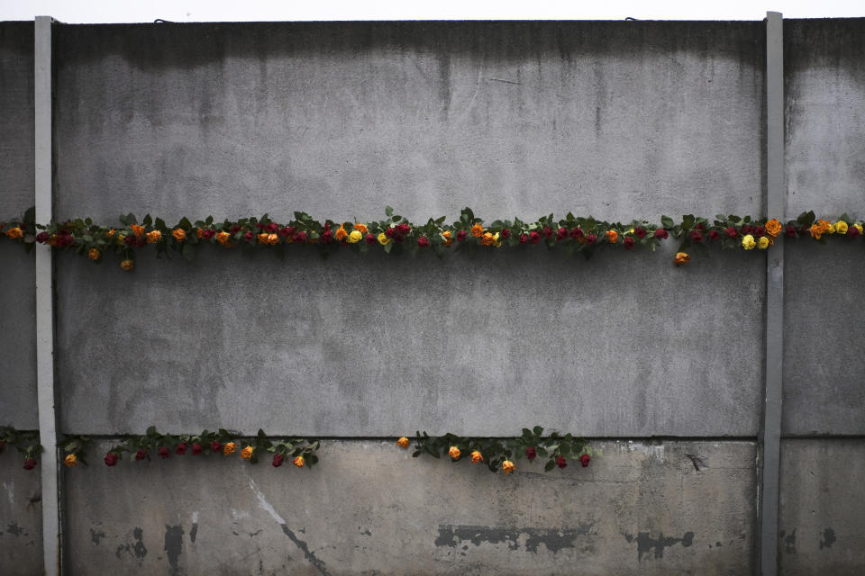 Flowers stuck in remains of the Berlin Wall during a commemoration ceremony to celebrate the 30th anniversary of the fall of the Berlin Wall at the Wall memorial side at Bernauer Strasse in Berlin, Saturday, Nov. 9, 2019. (AP Photo/Markus Schreiber)