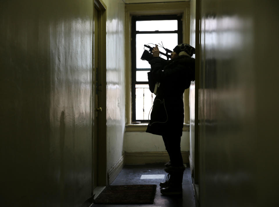 A reporter films the door of an apartment that was searched by police at 320 Mott St. in New York, Wednesday, Feb. 5, 2014. Four people are in custody on drug charges after police executed search warrants at three apartments in the building. (AP Photo/Seth Wenig)