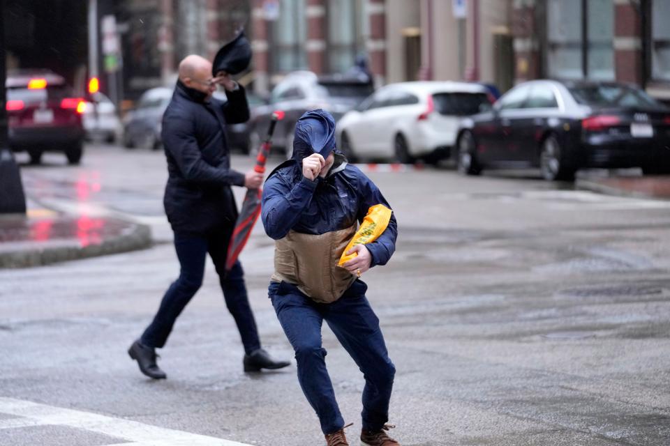 Pedestrians are buffeted by wind as they cross a street, Monday, Dec. 18, 2023, in Boston. A storm moving up the East Coast brought heavy rain and high winds to the Northeast on Monday, threatening flooding, knocking out power to hundreds of thousands. (AP Photo/Steven Senne)