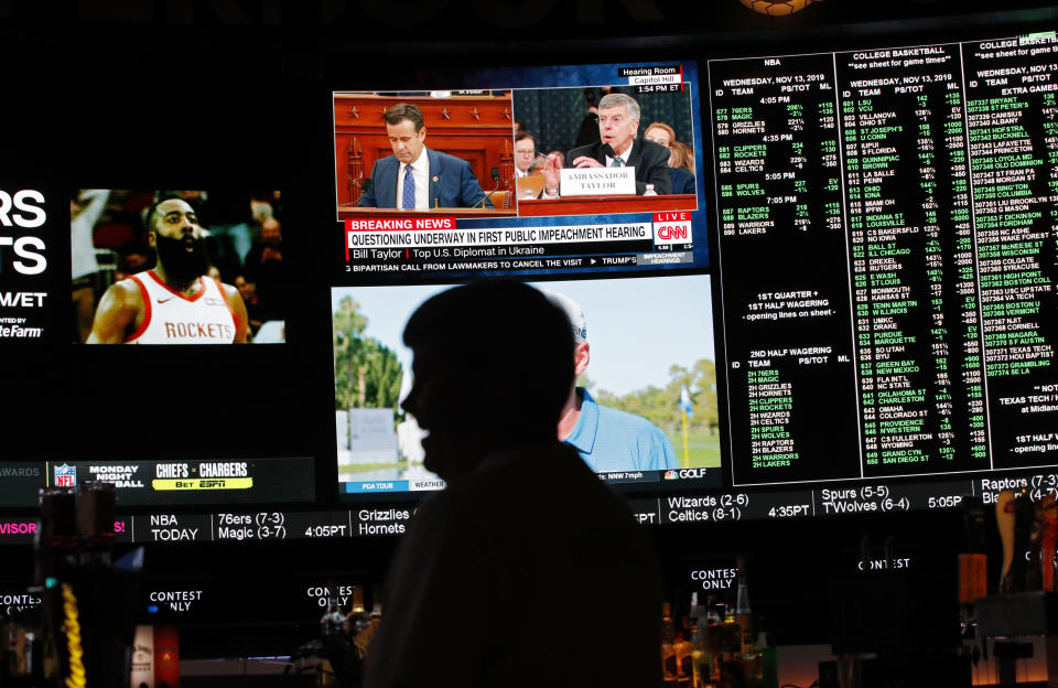 The first public impeachment hearing of President Donald Trump plays on a screen along with sports at the Superbook sports book inside the Westgate casino-hotel Wednesday, Nov. 13, 2019, in Las Vegas. (AP Photo/John Locher)