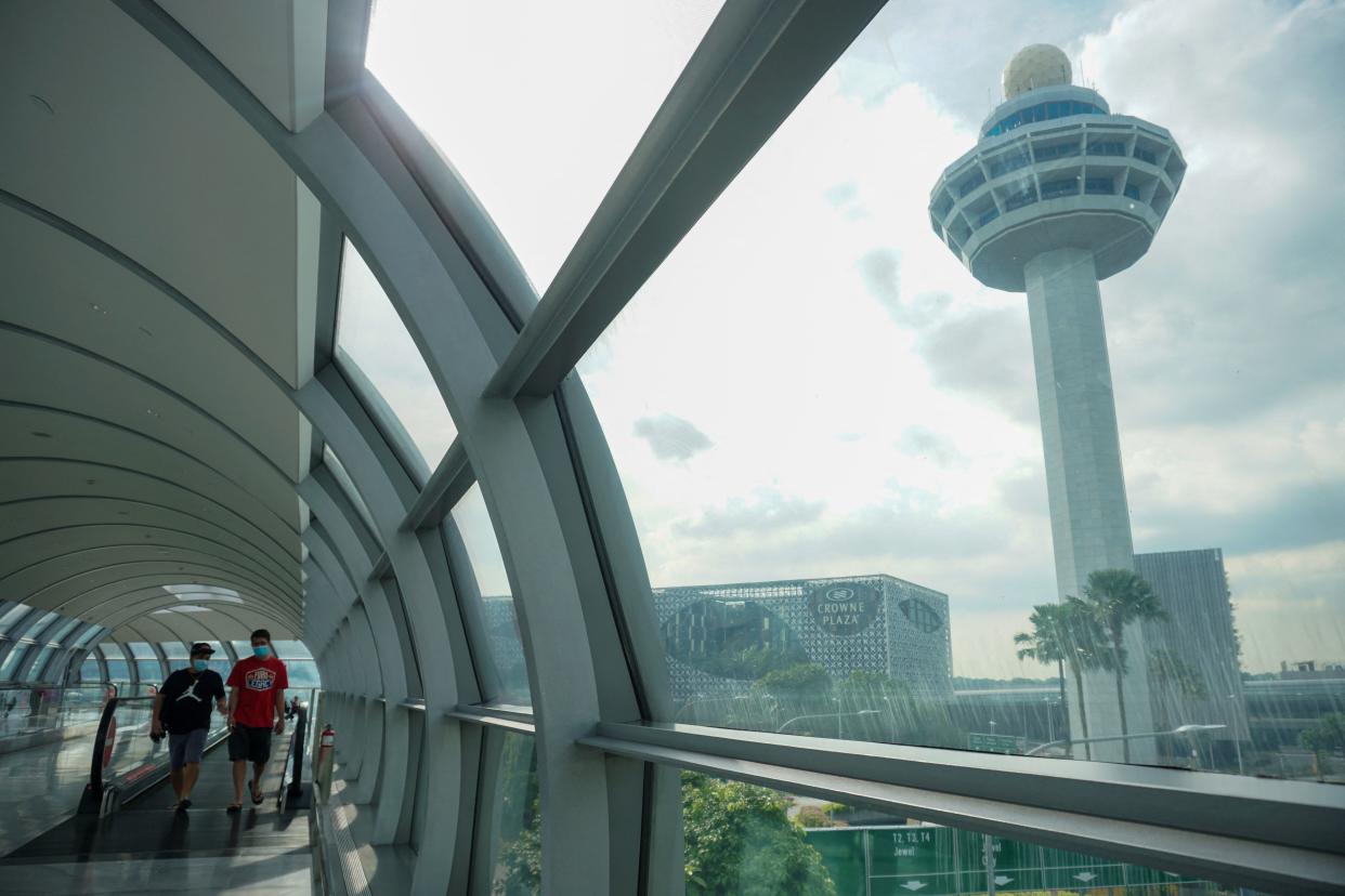 People walk along the link bridge to a terminal at Changi International Airport in Singapore on November 18, 2021. (Photo by Roslan RAHMAN / AFP) (Photo by ROSLAN RAHMAN/AFP via Getty Images)