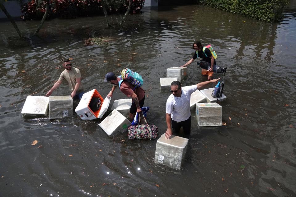 People try and save valuables as they wade through flood waters in the Edgewood neighborhood of Fort Lauderdale, Fla., April 13, 2023. Over 25 inches of rain fell in South Florida since Monday, causing widespread flooding.